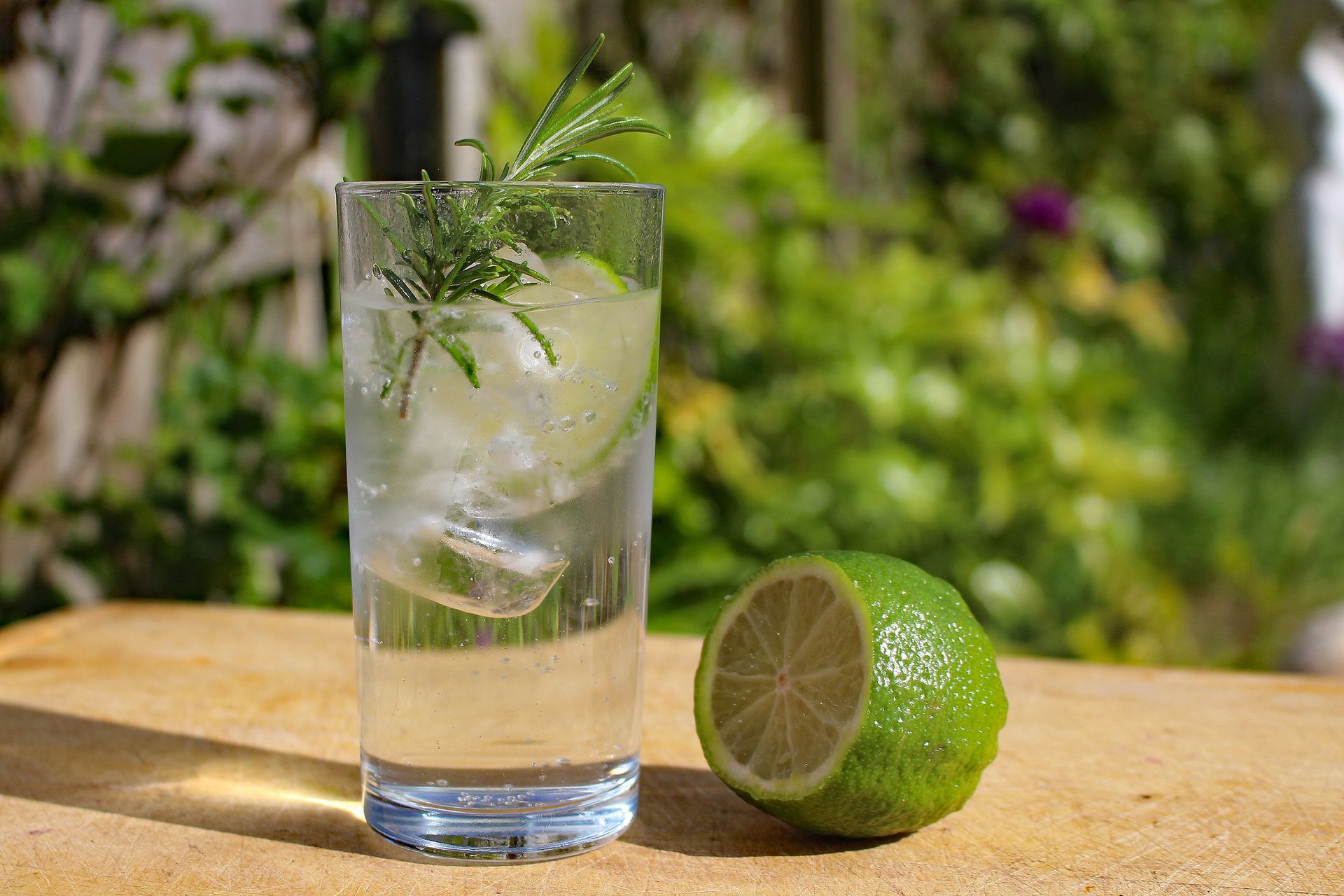A close-up of a gin and tonic with lime and rosemary, perfect for summer refreshment.