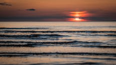 日落时分，天空充满活力，海面波光粼粼，景色宁静