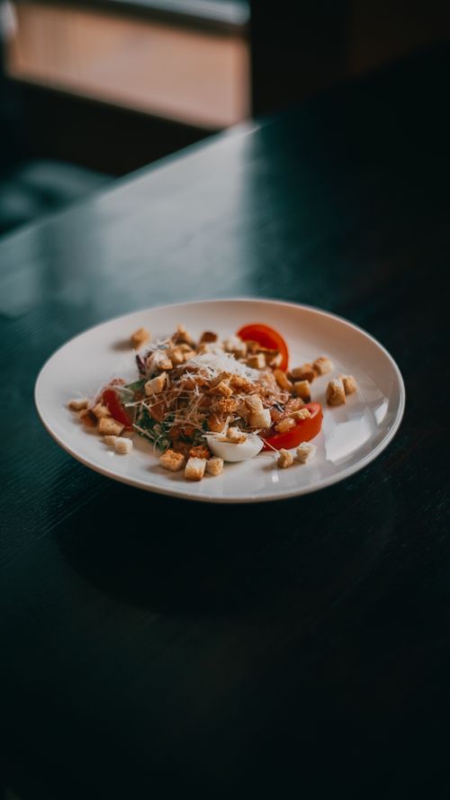 Free A gourmet salad featuring quail eggs, croutons, and tomatoes on a stylish white plate. Stock Photo
