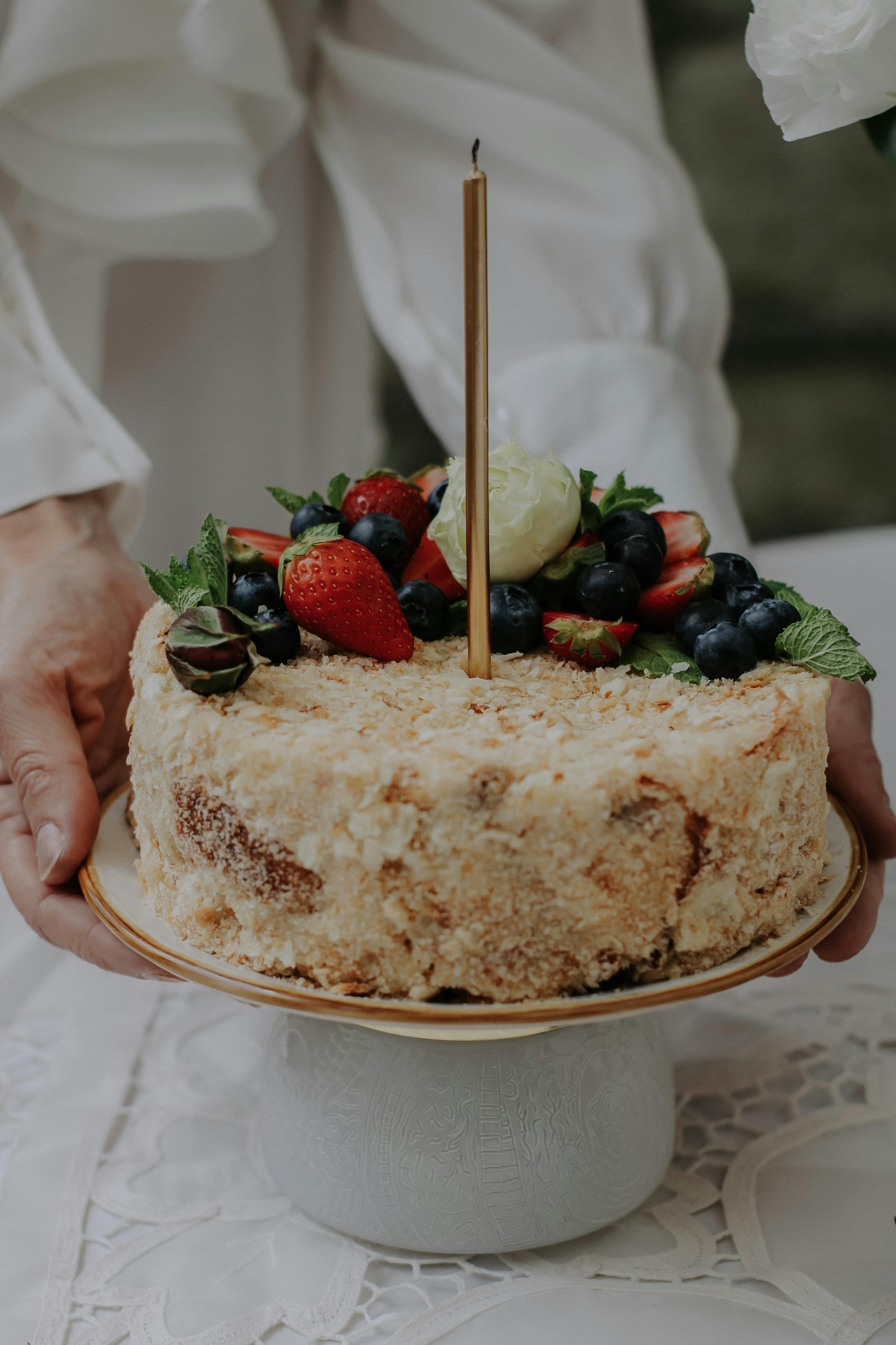 Бесплатные стоковые фото на тему cakestand, вертикальный выстрел, готовы  съесть, десерт, клубника, потворство, руки, свеча, сладкий, стол, торт,  фотография еды, черника, ягоды