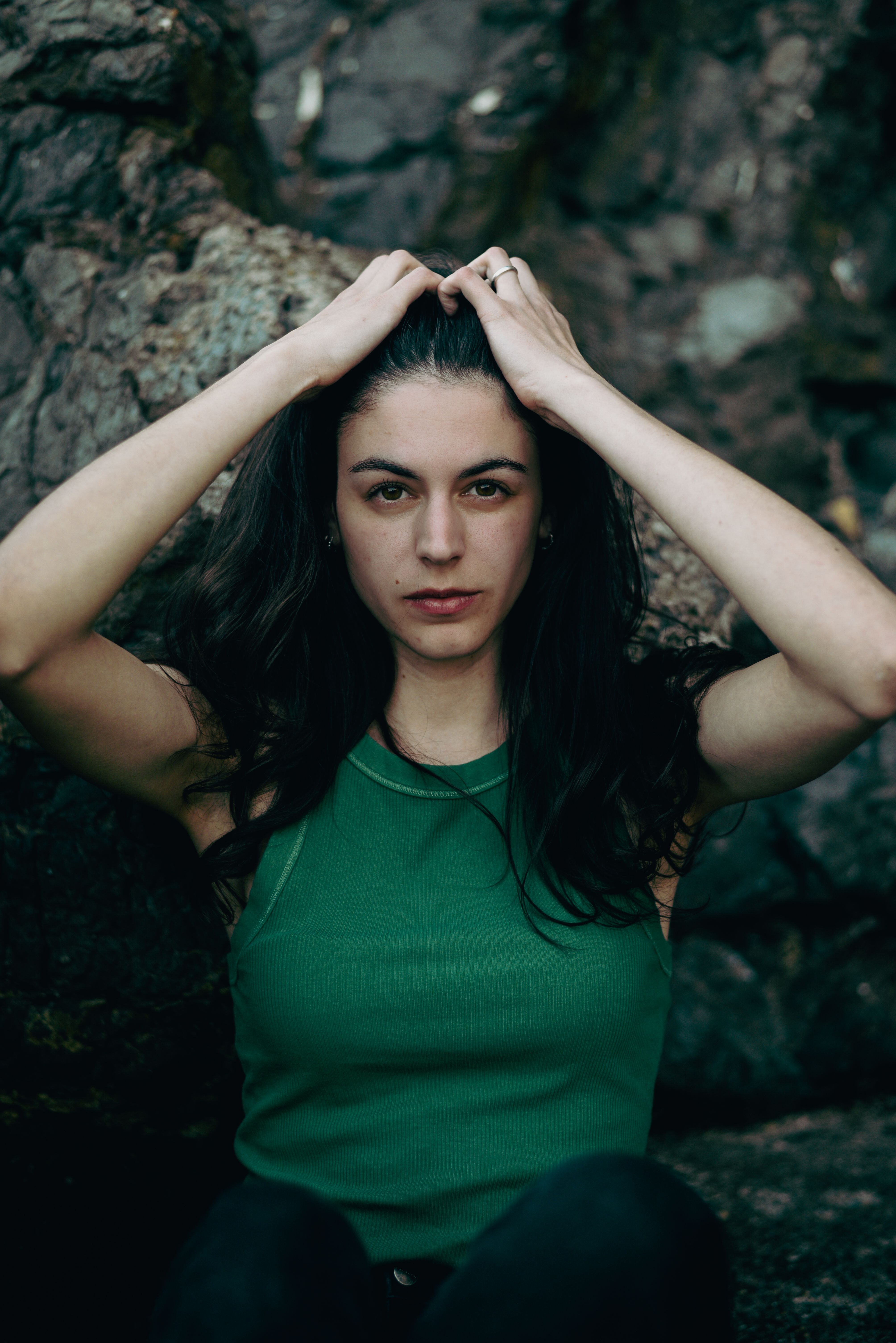 Stylish portrait of a woman in green by a rocky seashore in Genoa.