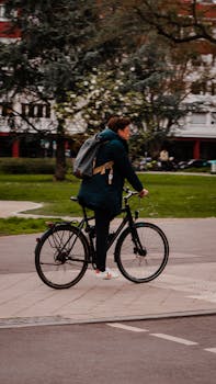 Person cycling with a backpack through a park in Heidelberg, Germany. City life and recreation.