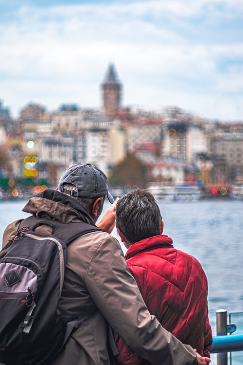 Two Men Looking at Townscape Behind a Water