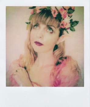 Artistic portrait of a woman with elf ears wearing a floral garland and a dreamy expression.