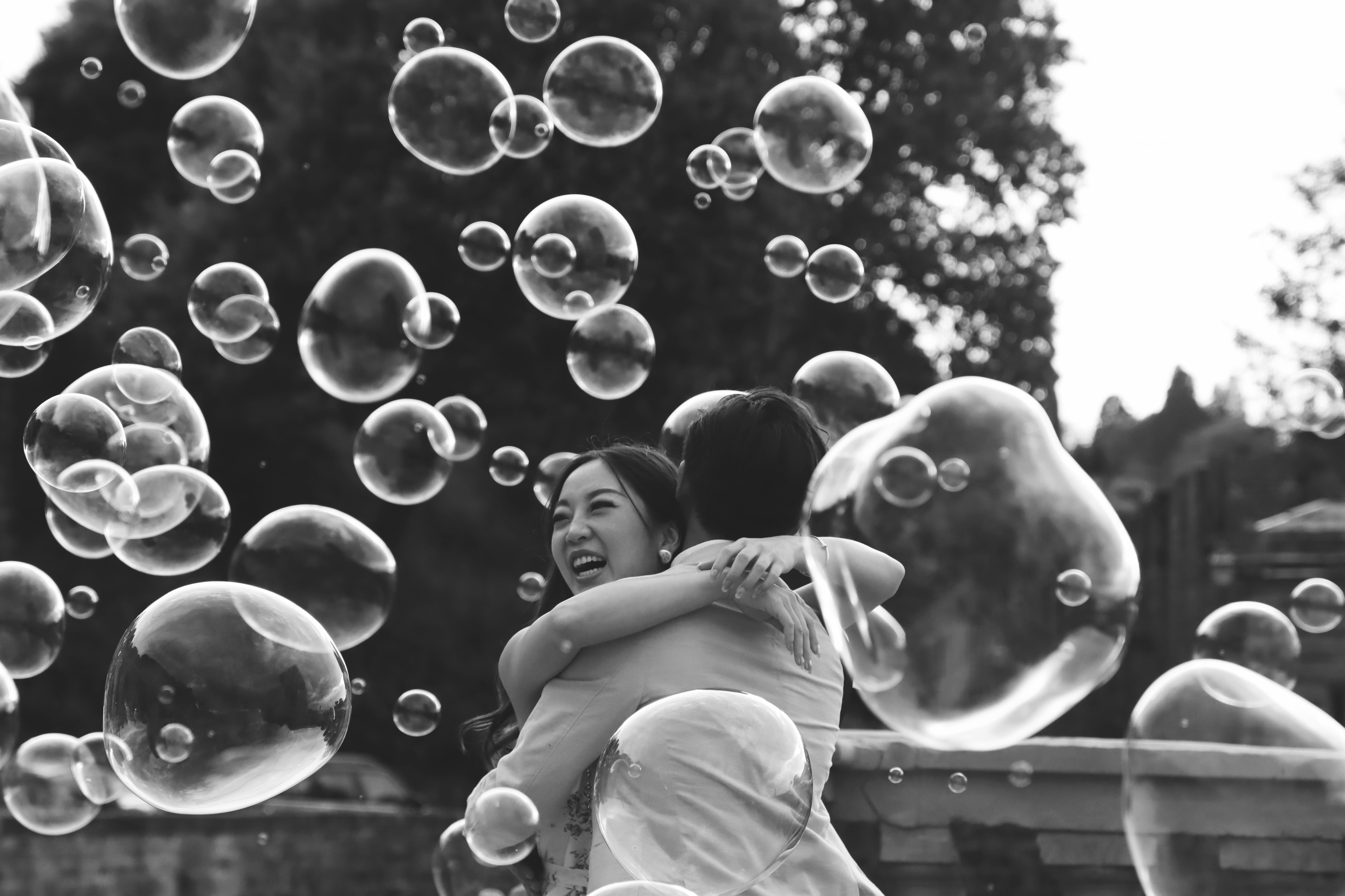 A happy couple embraces amidst floating bubbles in Florence, Italy.