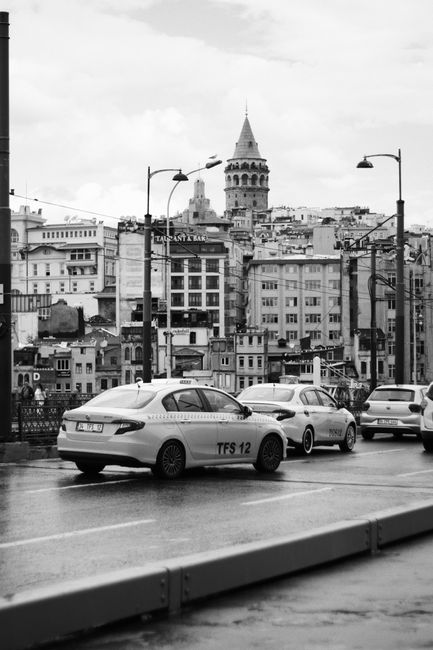 Black and white view of cars on city street with Galata Tower in Istanbul, Turkey.