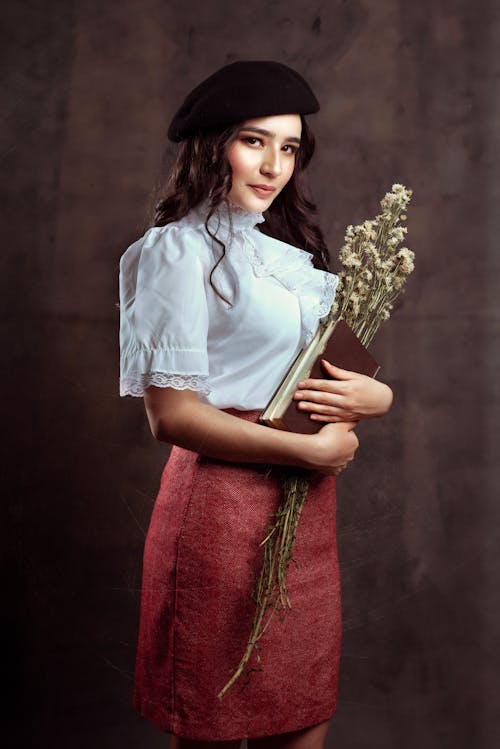 Woman in a Skirt and a Beret Holding a Bunch of Flowers