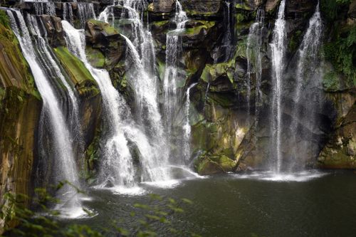 Free A breathtaking waterfall flowing over moss-covered rocks in a serene outdoor setting. Stock Photo