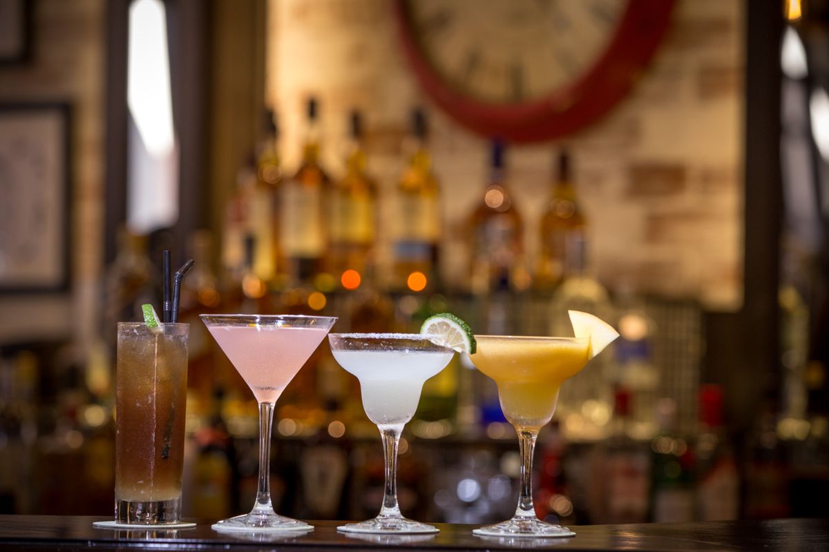 A line of cocktails on the bar in front of the back bar