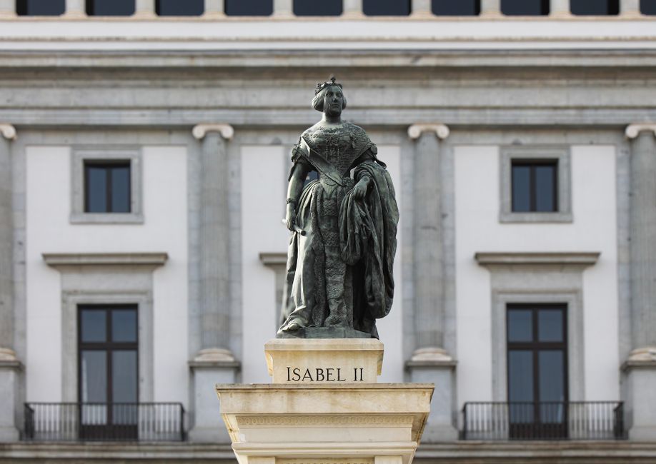 Elegante estatua de la Reina Isabel II frente a una fachada histórica en Madrid, España.
