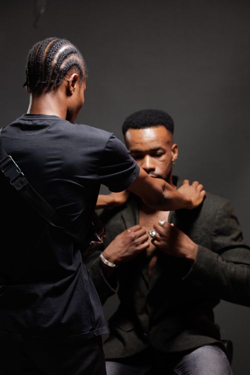 Free Two men in a studio setting adjusting suit. Fashion preparation captured. Stock Photo