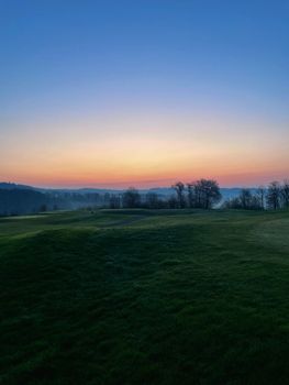 Stunning dusk view of a rural landscape with hills and trees at sunset.