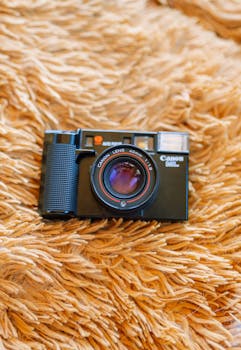 A classic retro camera resting on a soft orange blanket, evoking nostalgia.