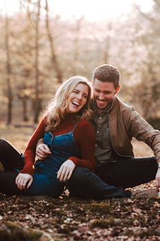 Happy couple laughing together in a sunny autumn forest in Colchester, England.