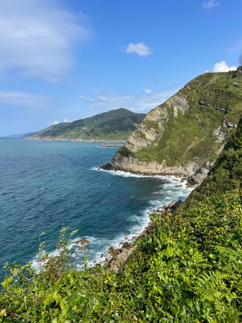 Free Breathtaking view of a steep coastal cliff with lush greenery, overlooking the blue sea under a clear sky. Stock Photo