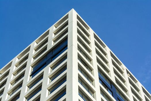 Contemporary apartment building facade in Delft against a clear blue sky.