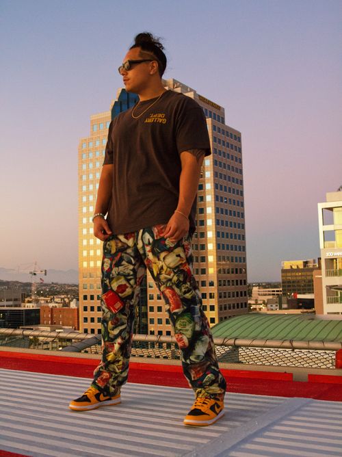 Free Young adult showcases eclectic style on urban rooftop at sunset with city skyline view. Stock Photo