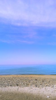 Peaceful sandy beach and calm sea under a clear blue sky, perfect for relaxation.