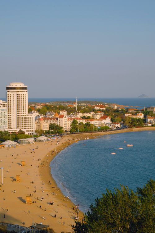 Free Aerial view of a bustling coastal city and beach with sandy shores and buildings. Stock Photo