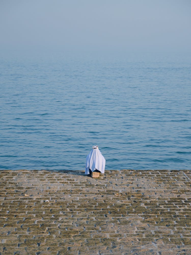 Back View Of A Person In A Muslim Head Covering In Front Of The Sea