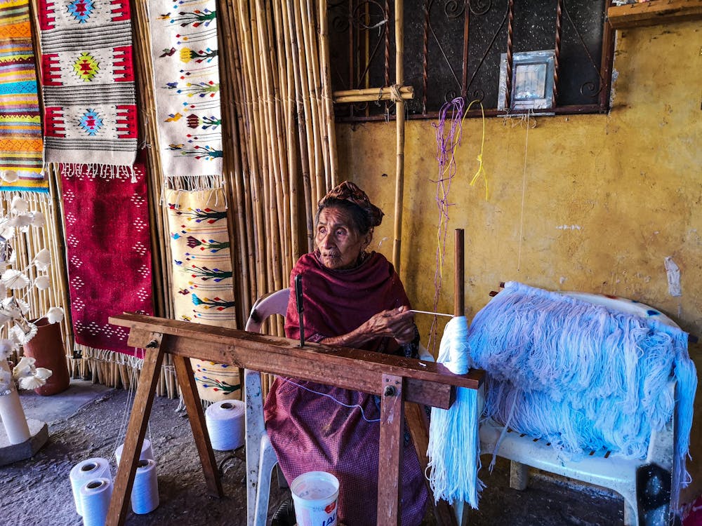 An Elderly Woman Weaving Rugs with Traditional Patterns · Free Stock Photo