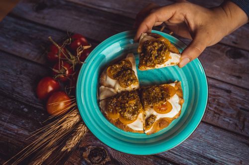 Free Rustic bruschetta with pesto and tomatoes on turquoise plate being served. Stock Photo