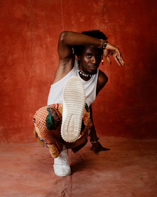 Energetic breakdancer in action against a vivid red backdrop, showcasing modern fashion and movement.
