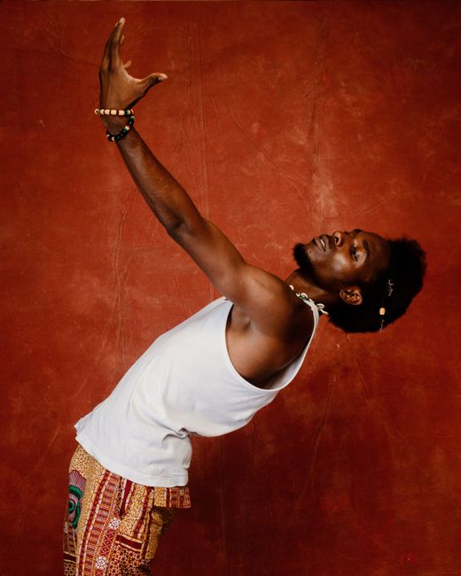 A fashionable man with a beard poses dynamically in a studio setting.