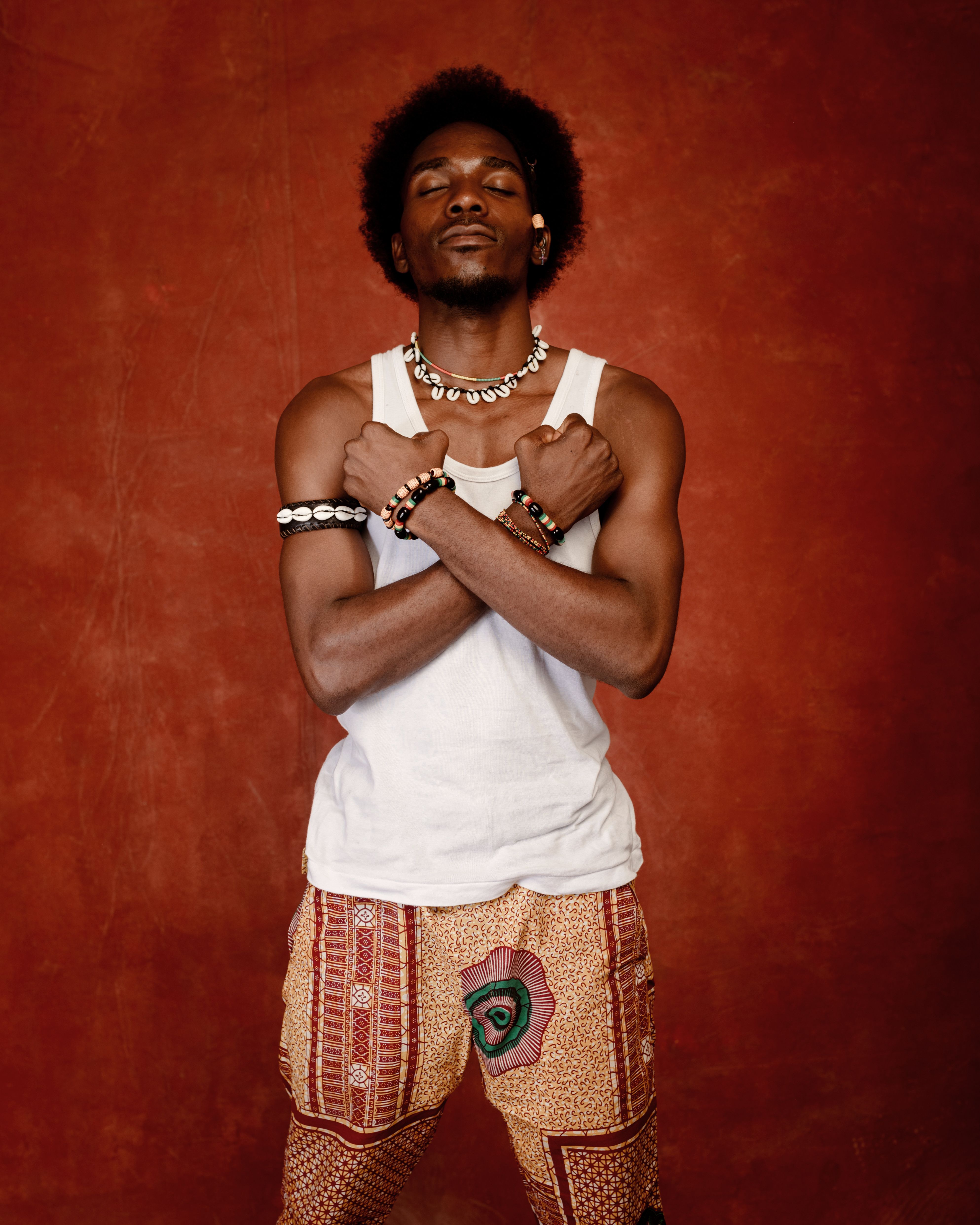 African man with arms crossed, wearing traditional attire in studio.