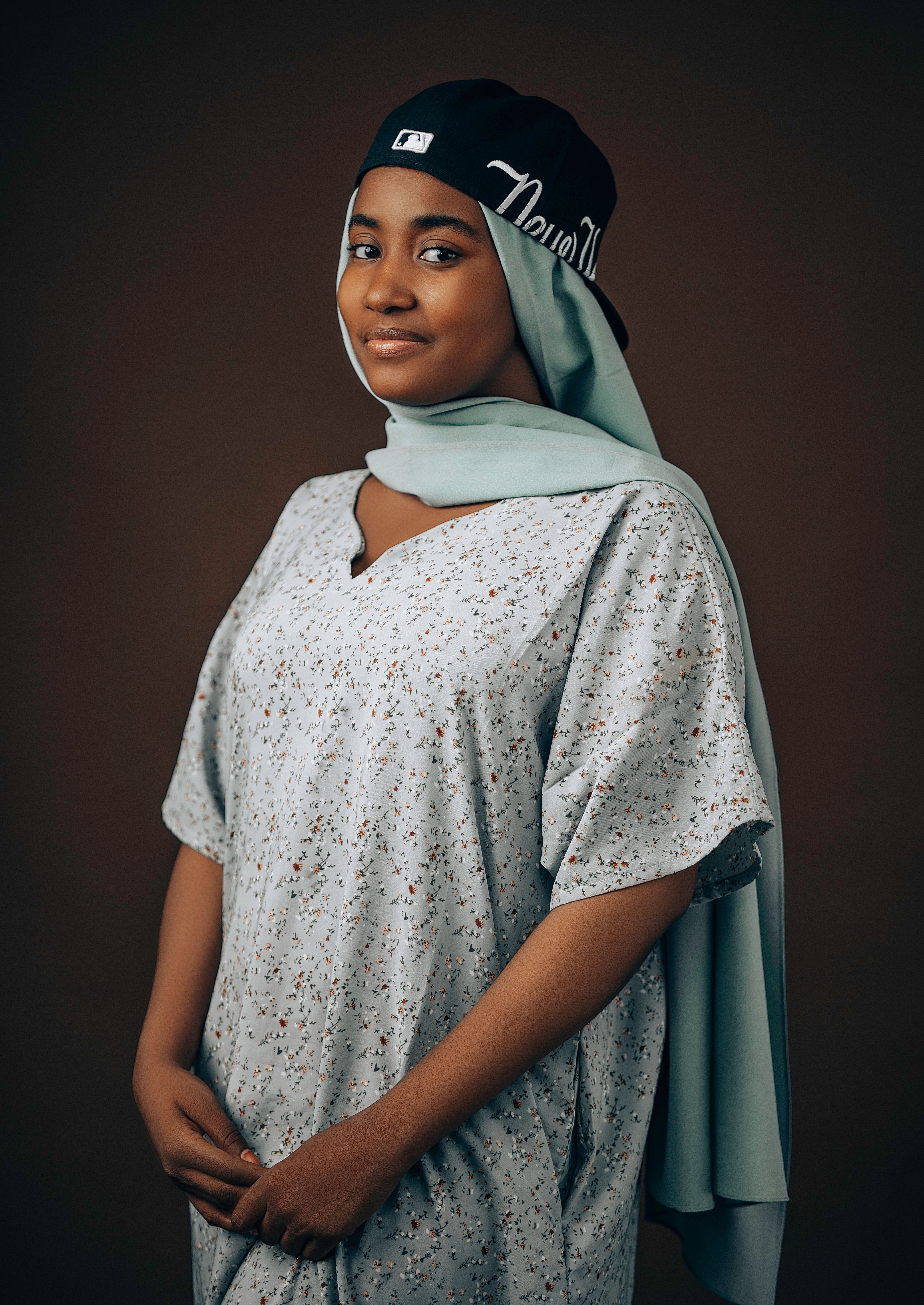 Charming portrait of a young woman wearing a headscarf and cap, showcasing modern fashion and cultural identity.