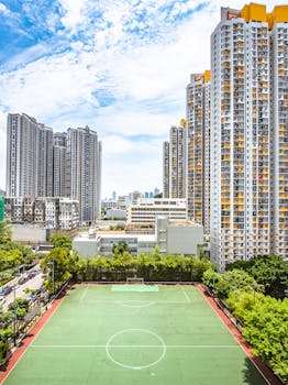 A vibrant cityscape with a soccer field surrounded by towering skyscrapers, offering a glimpse of urban athletic life.