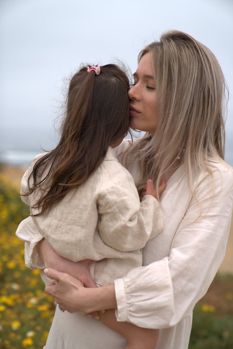 Young Woman Holding Child In Hands In Field