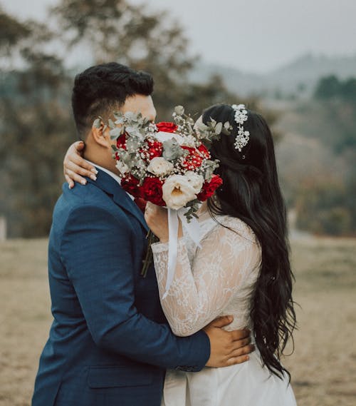 Free Bride and Groom Kissing Behind the Wedding Bouquet Stock Photo