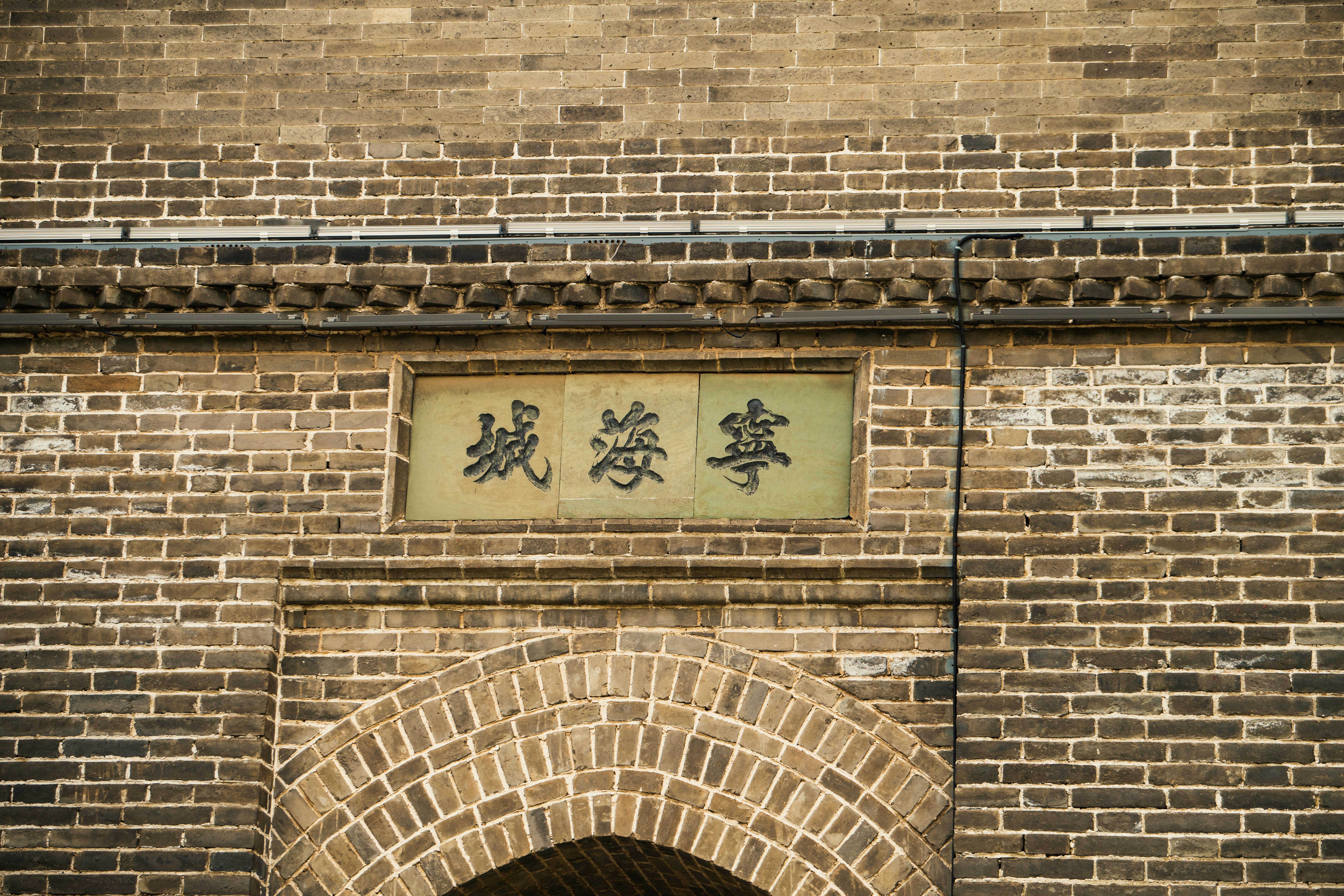 Detailed view of a traditional Chinese brick wall featuring intricate design and ancient writing.