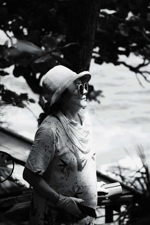 Free Black and white image of a senior woman in sunglasses and hat, outdoors. Stock Photo