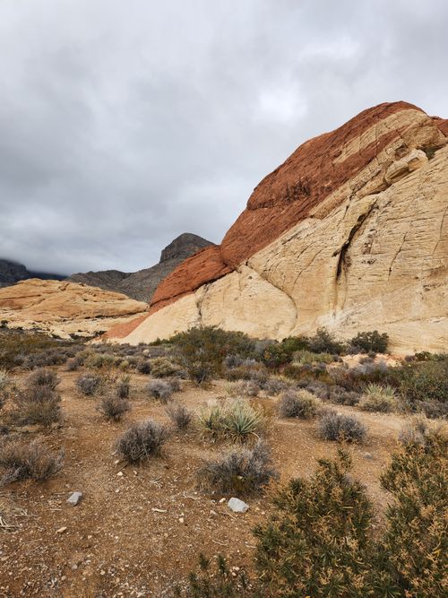 Free Discover a captivating arid desert scene featuring striking red and beige rock formations under a cloudy sky. Stock Photo