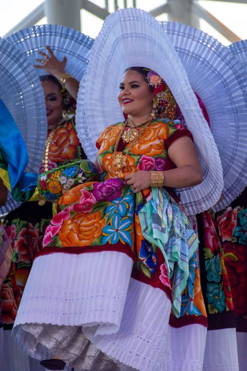 Free Colorful portrait of a woman in traditional Mexican attire with floral patterns and a white sombrero. Stock Photo