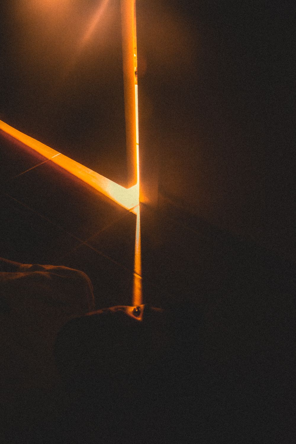 Warm light spilling through the gap of a door left ajar in a dark room