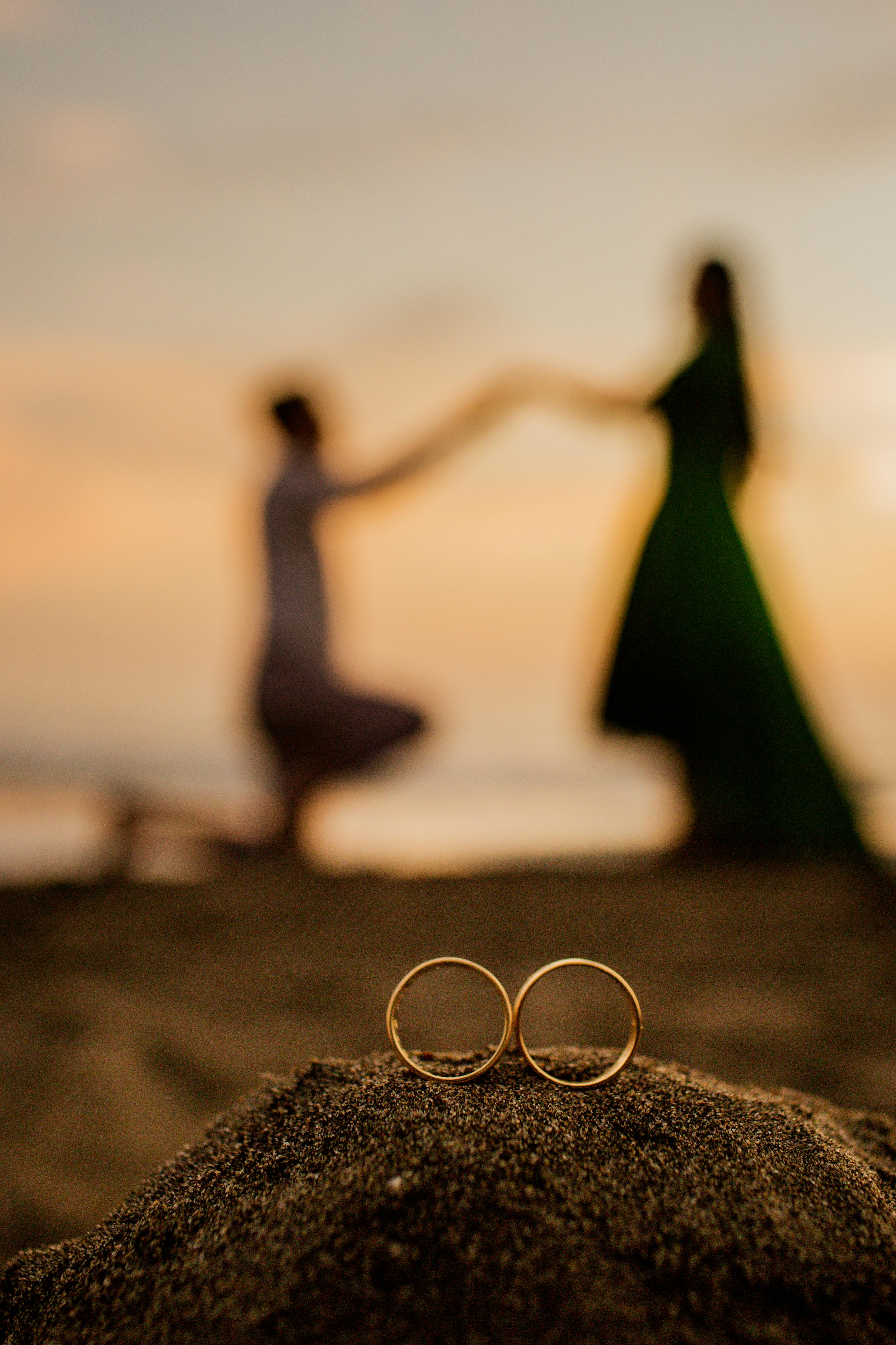 Capturing a romantic proposal scene with golden rings on a beach at sunset.