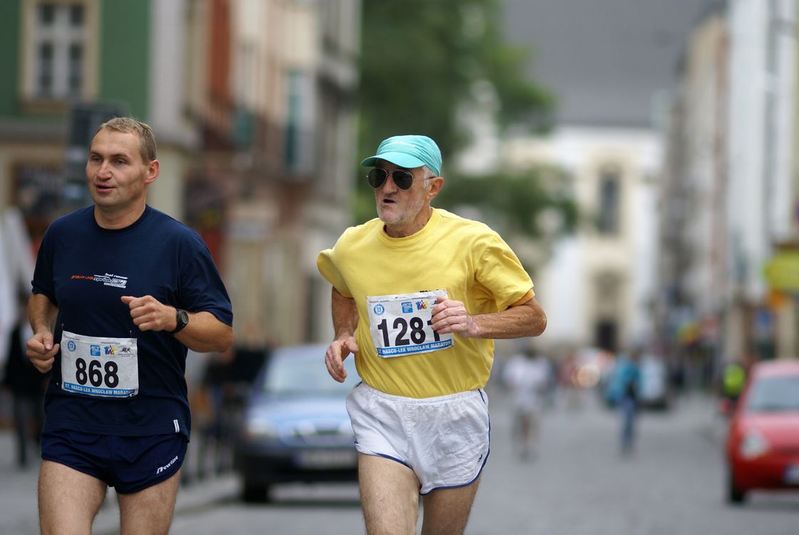 Two men running in a race on a city street · Free Stock Photo