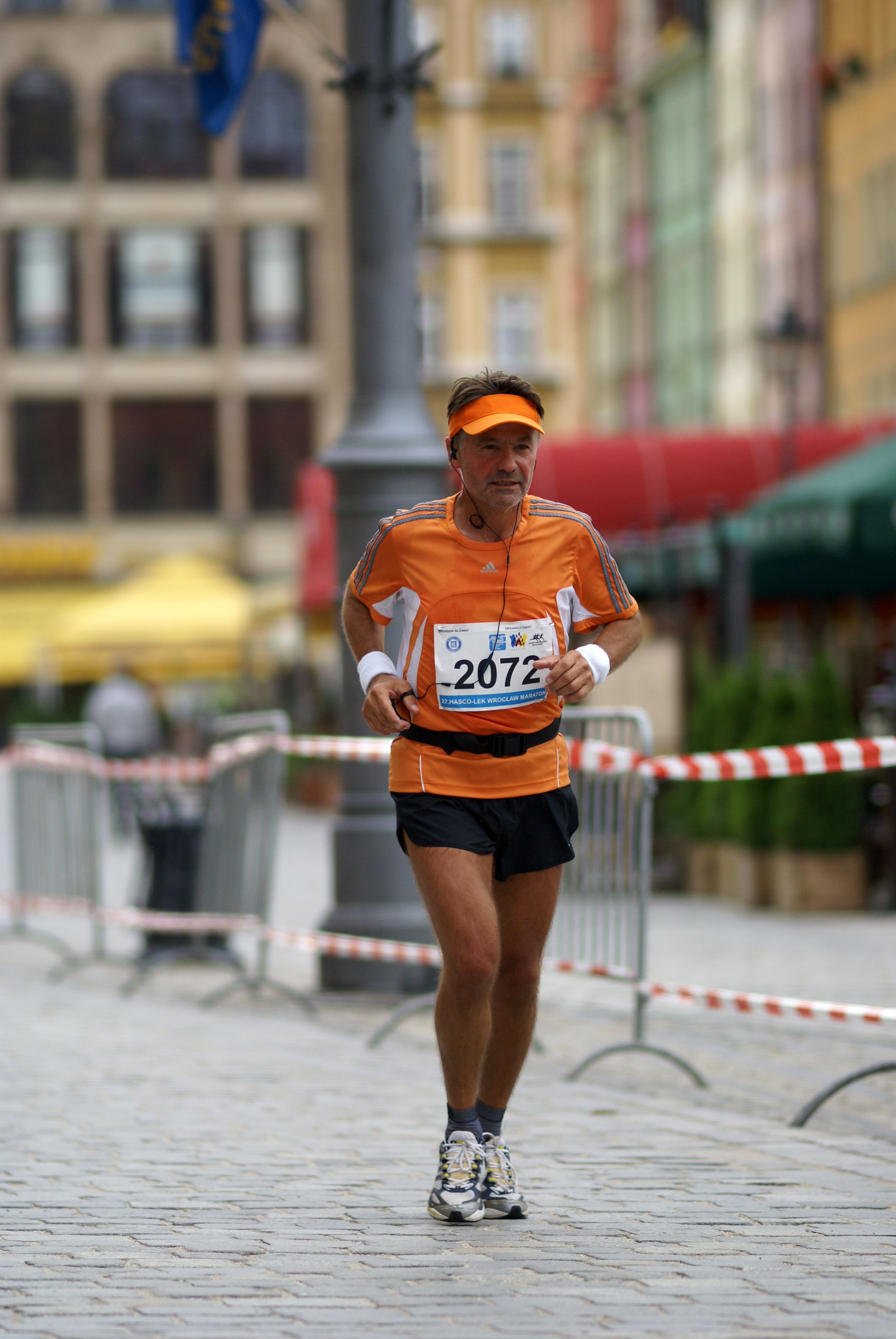 A man running a marathon through the streets of Wrocław, showcasing determination and fitness.