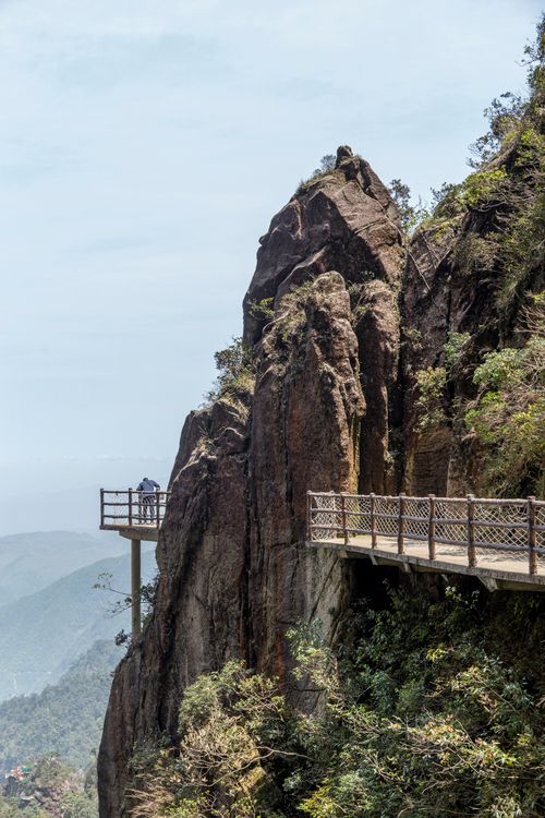 Free Elevated wooden footbridge on a rocky cliffside offering stunning mountain views. Stock Photo