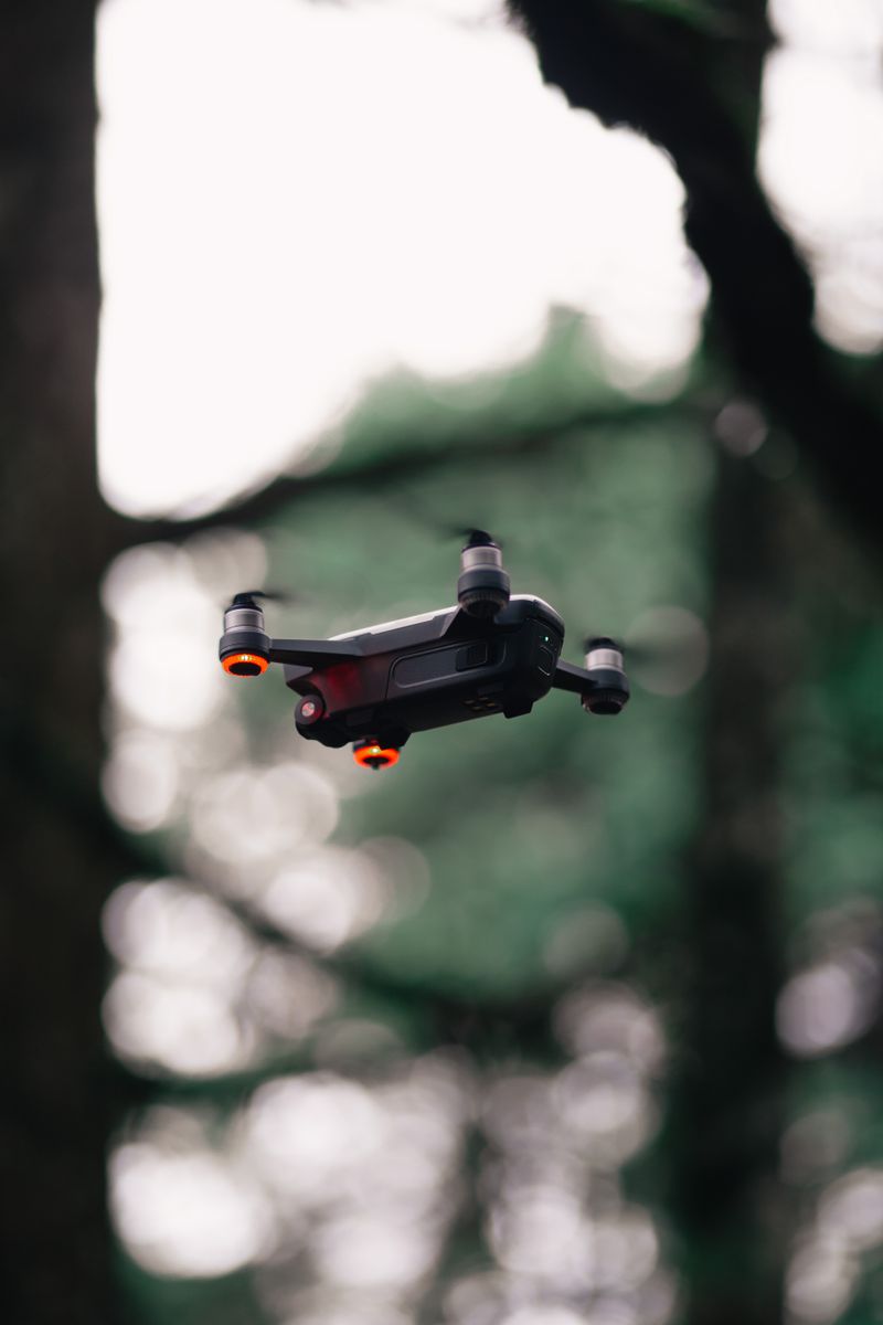 A black quadcopter micro-drone hovers mid-flight
