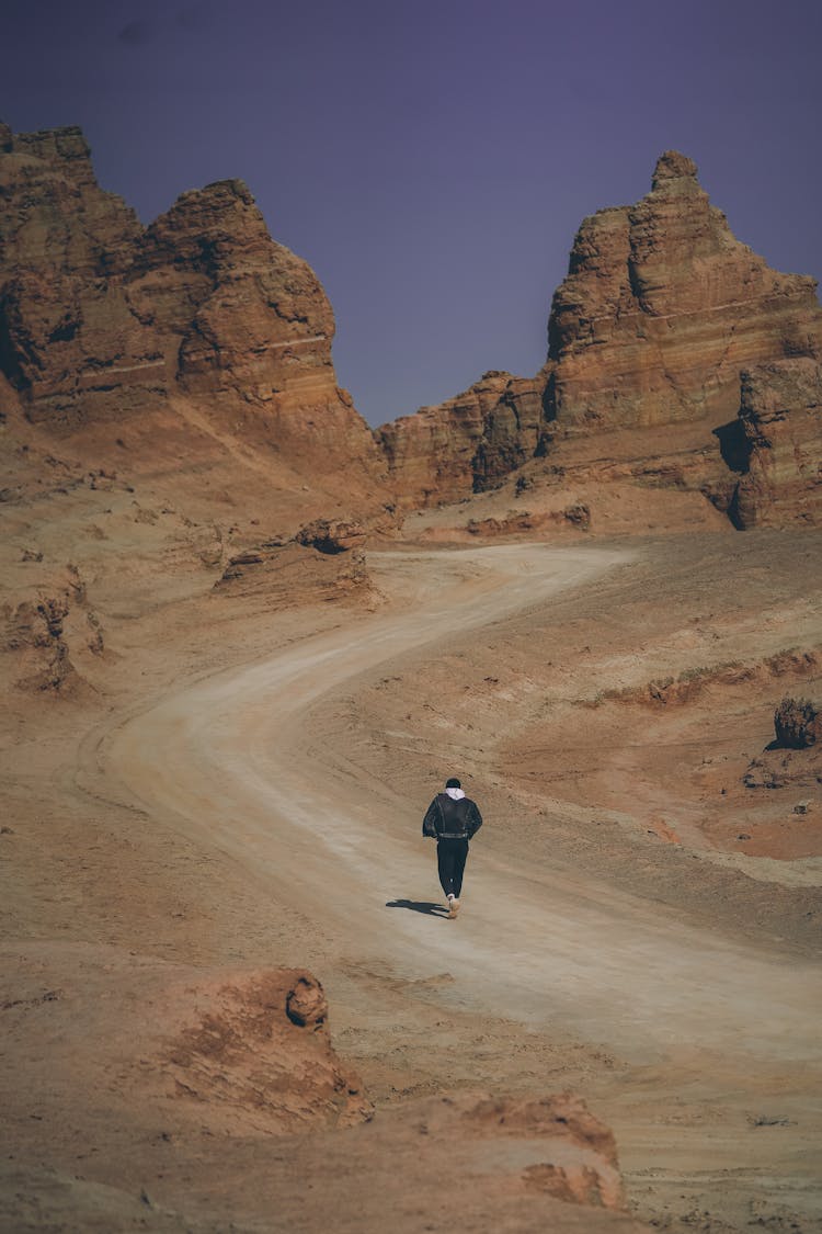 Hiker On Path Through Rugged Mountains