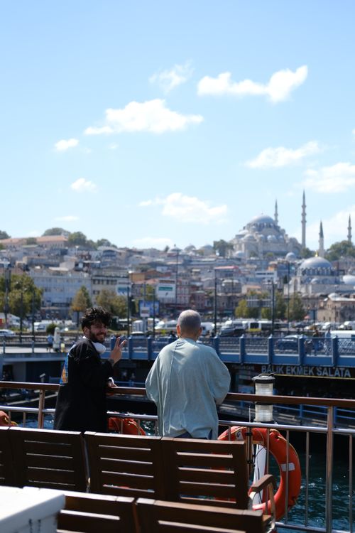 Free Two men on a ferry enjoying a clear day in Istanbul with the cityscape in the background. Stock Photo