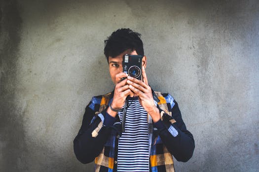 Portrait of a young man using a vintage camera against a textured background.