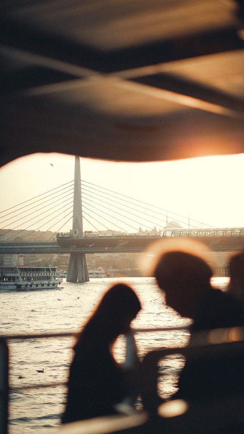 Free Silhouetted figures on a boat with Galata Bridge and sunset in Istanbul. Stock Photo