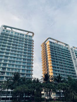Low angle view of modern high-rise buildings surrounded by palm trees in an urban setting.
