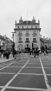 Black and white photo of a bustling London street with classic architecture.