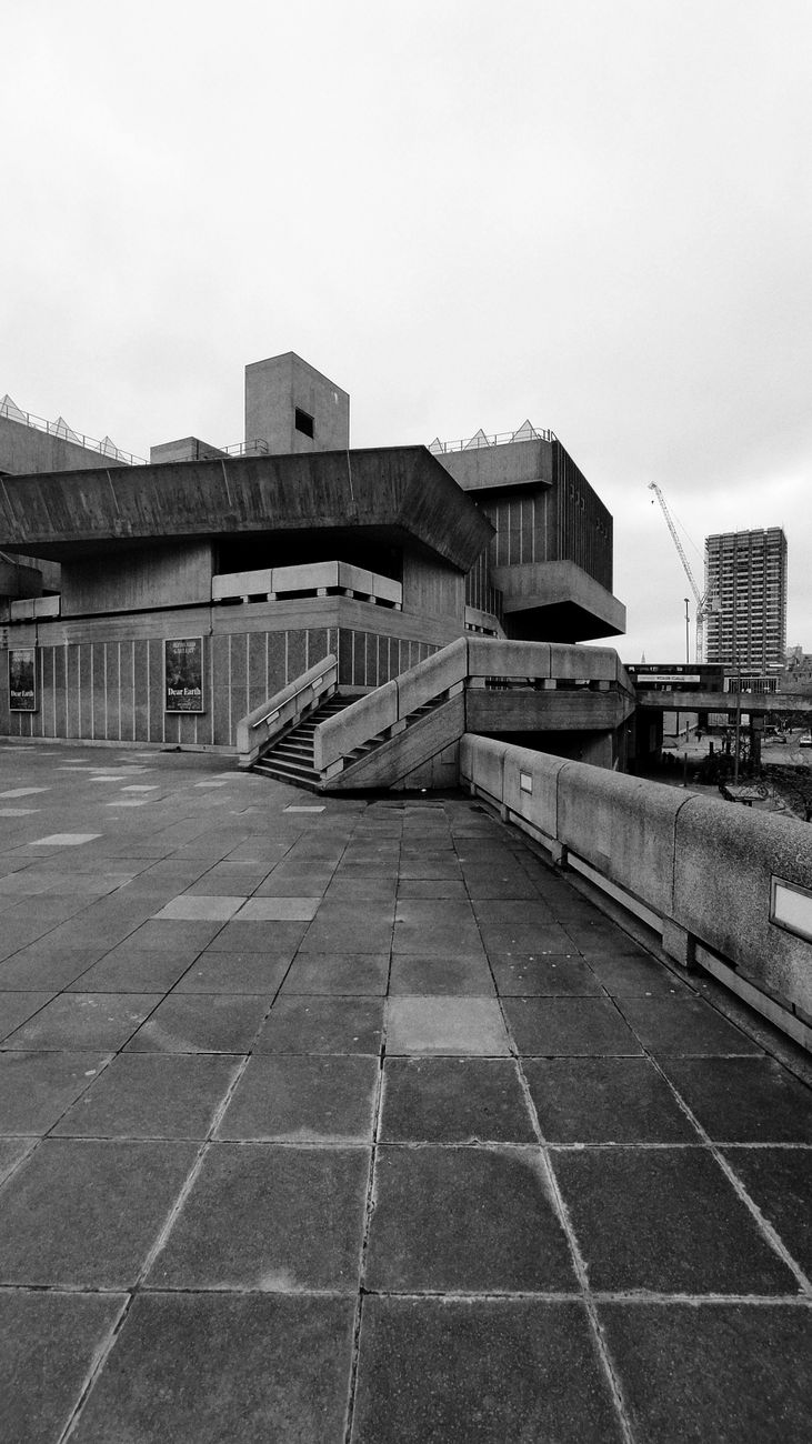 Black and white image of brutalist architecture in an urban setting with concrete structures.. black, white, image